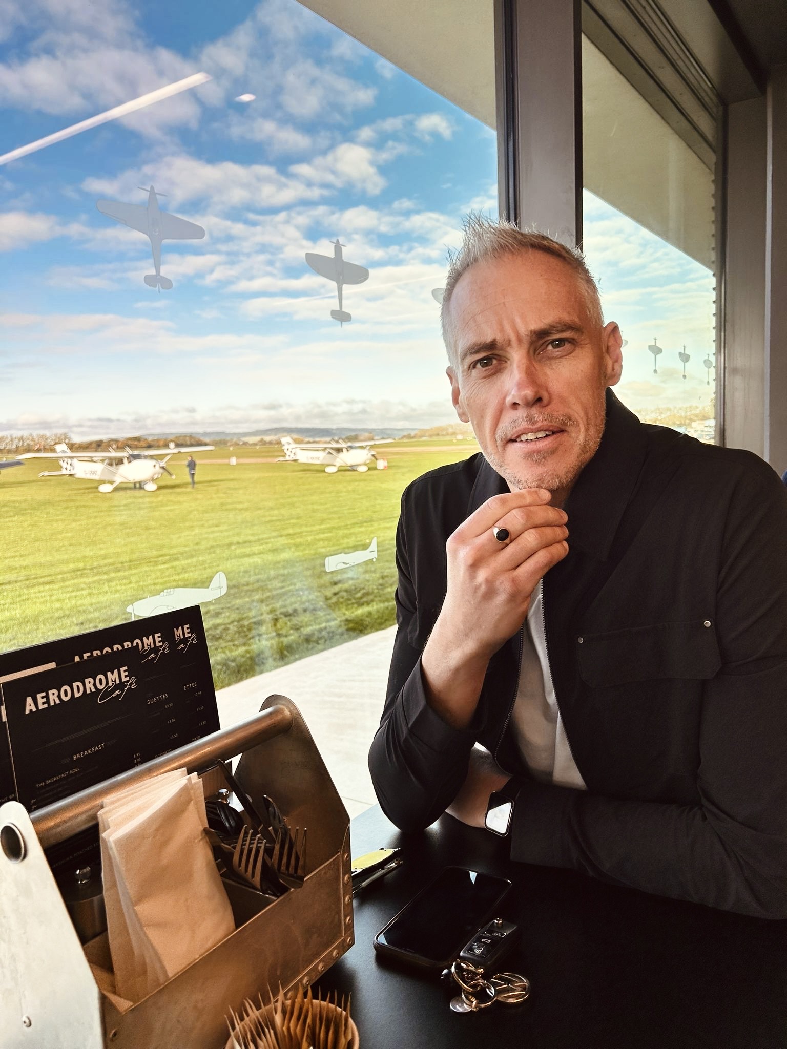 Ben Glover smiles at the camera with an airfield in the background.