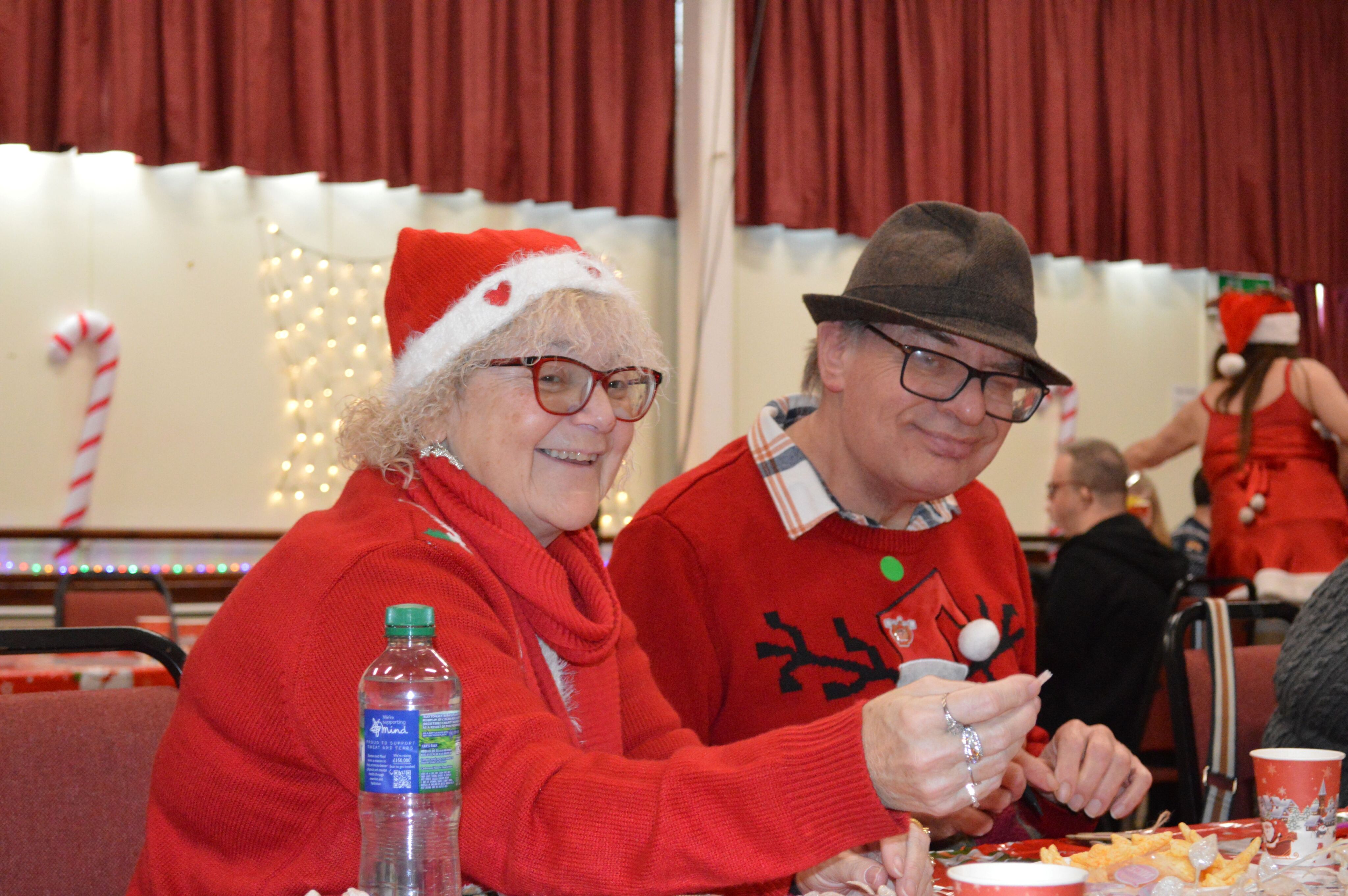 Dressed in festive red sweaters and holiday hats, two party goers enjoying the Christmas party.