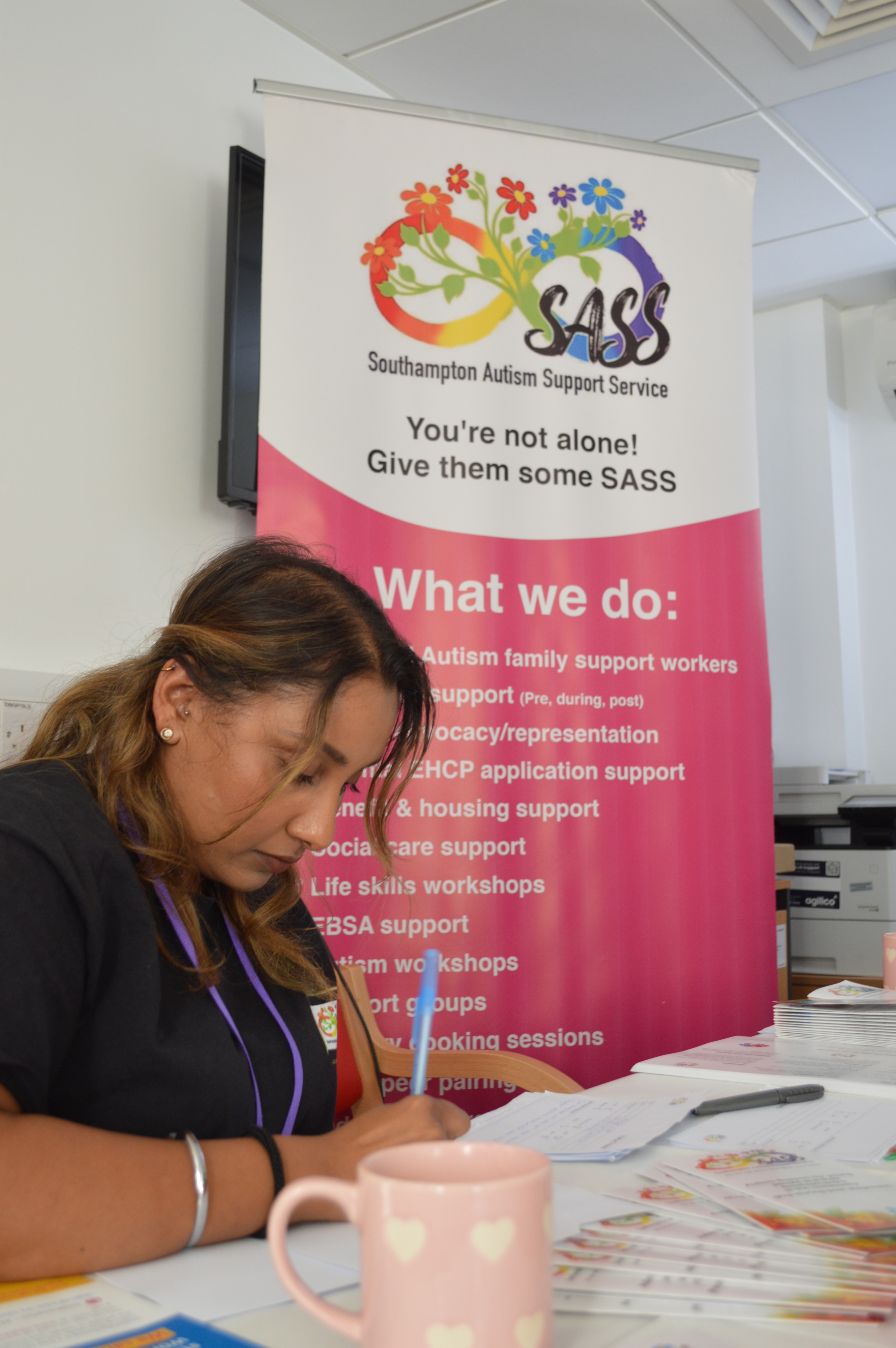 A colleague from SASS sits in front of an information sign writing.