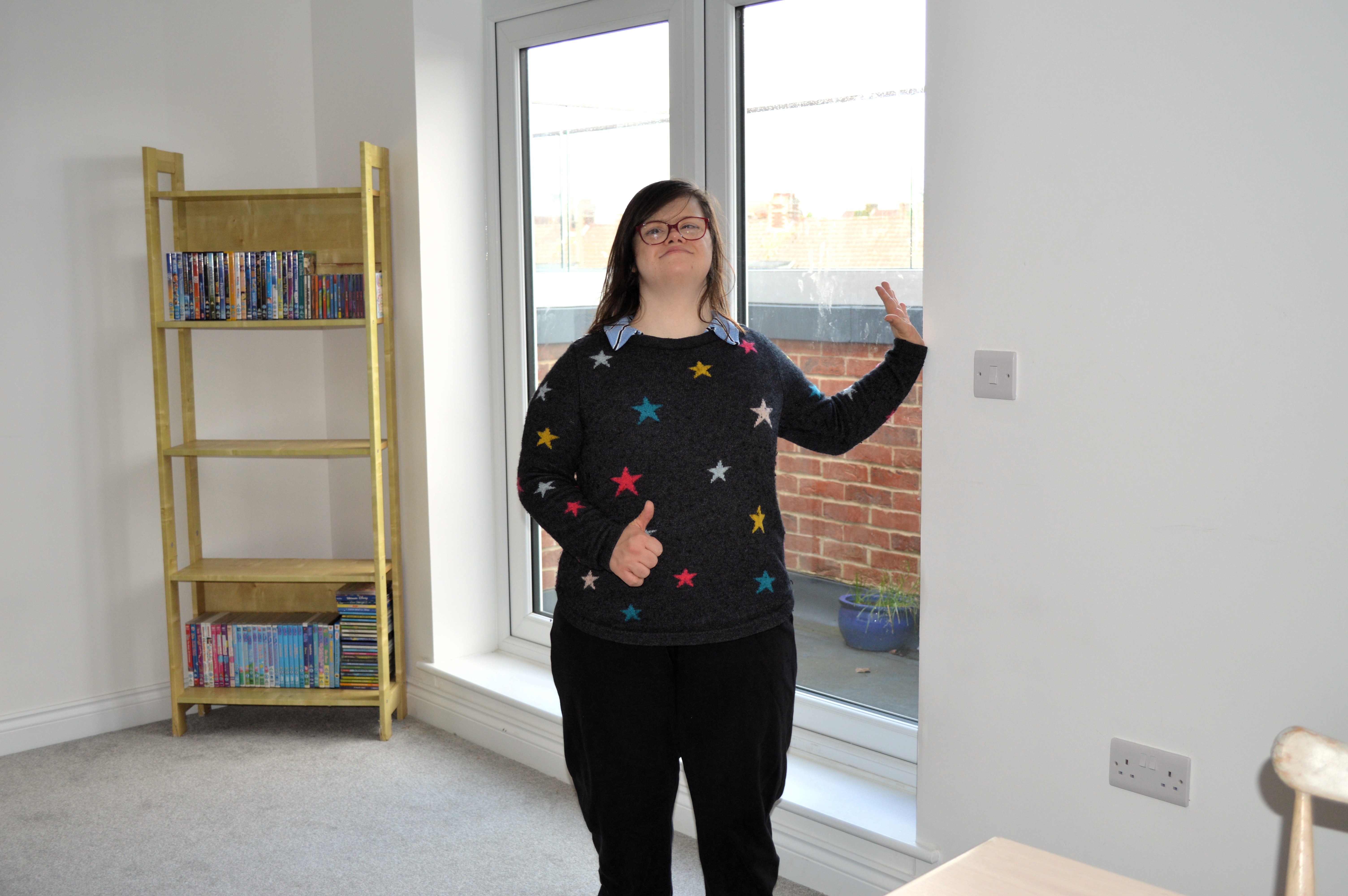 Rhi stands in front of her balcony doors.