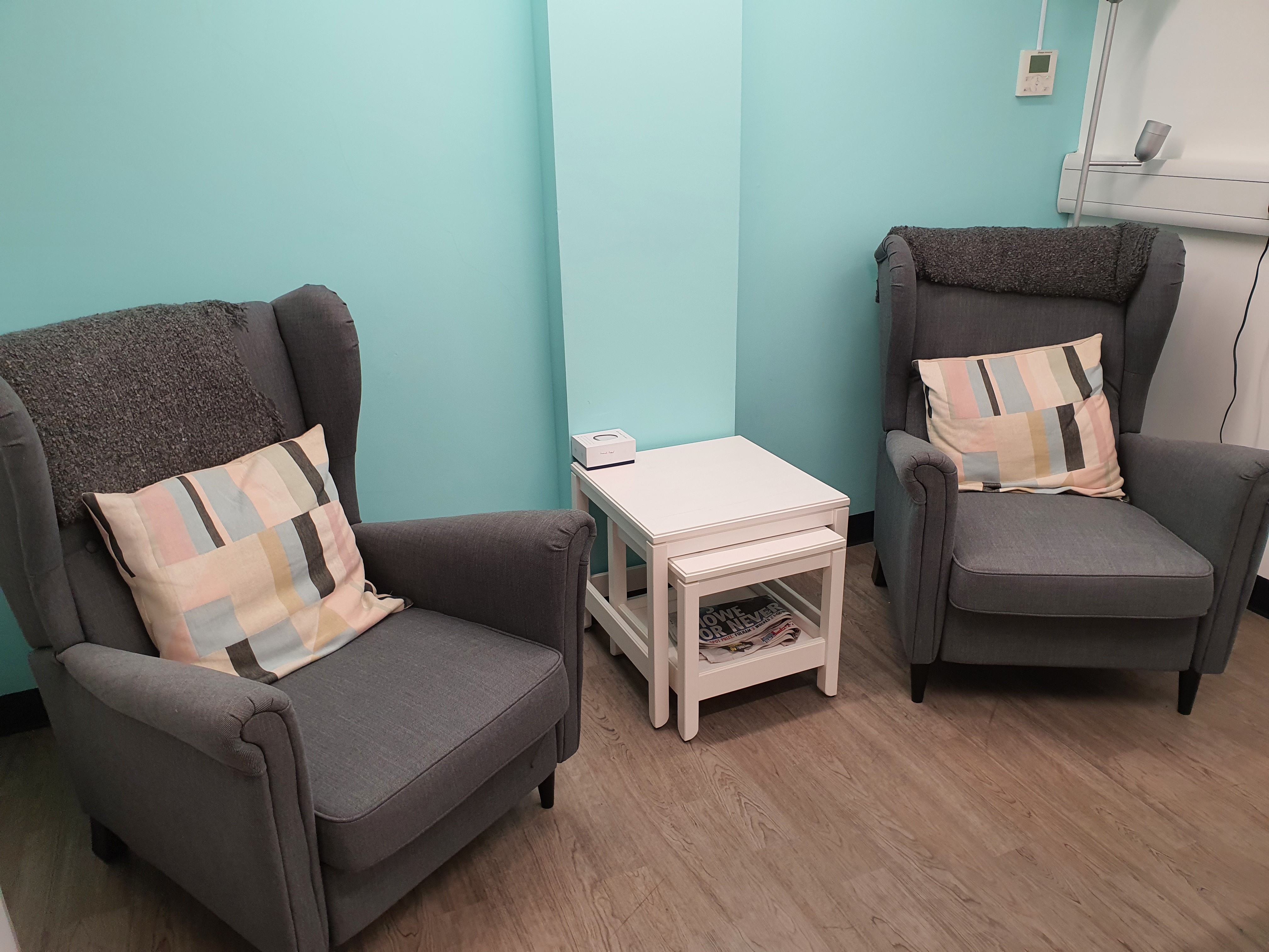 Inside one of the spaces - two grey arm chairs with a light blue wall