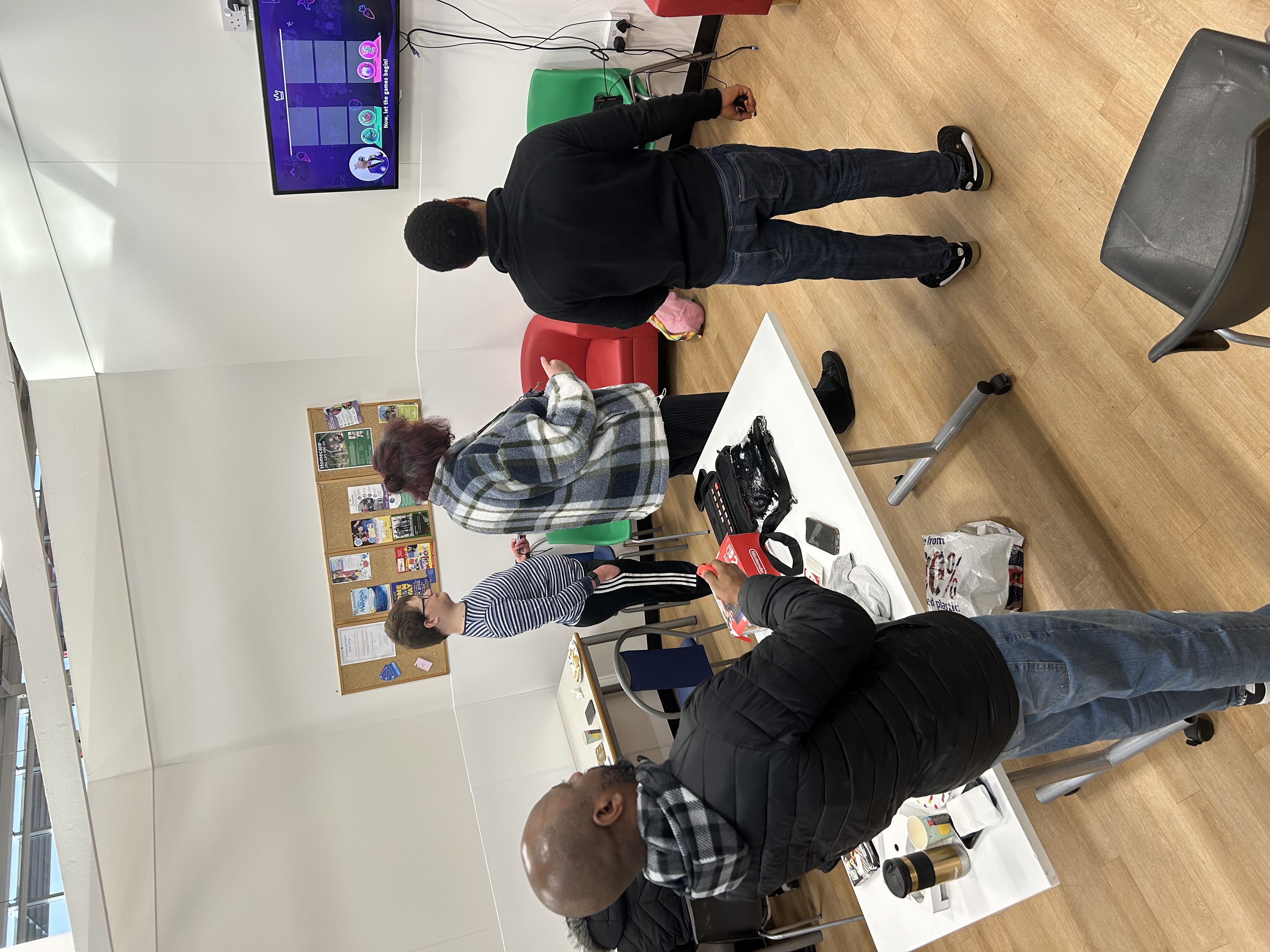 Four people looking at a TV screen, all playing a game together